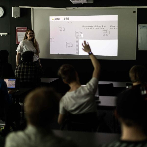 Elev räcker upp handen i klassrum.