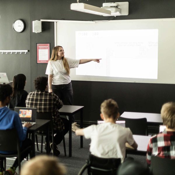 Person pekar på presentation på vägg inför en klass.