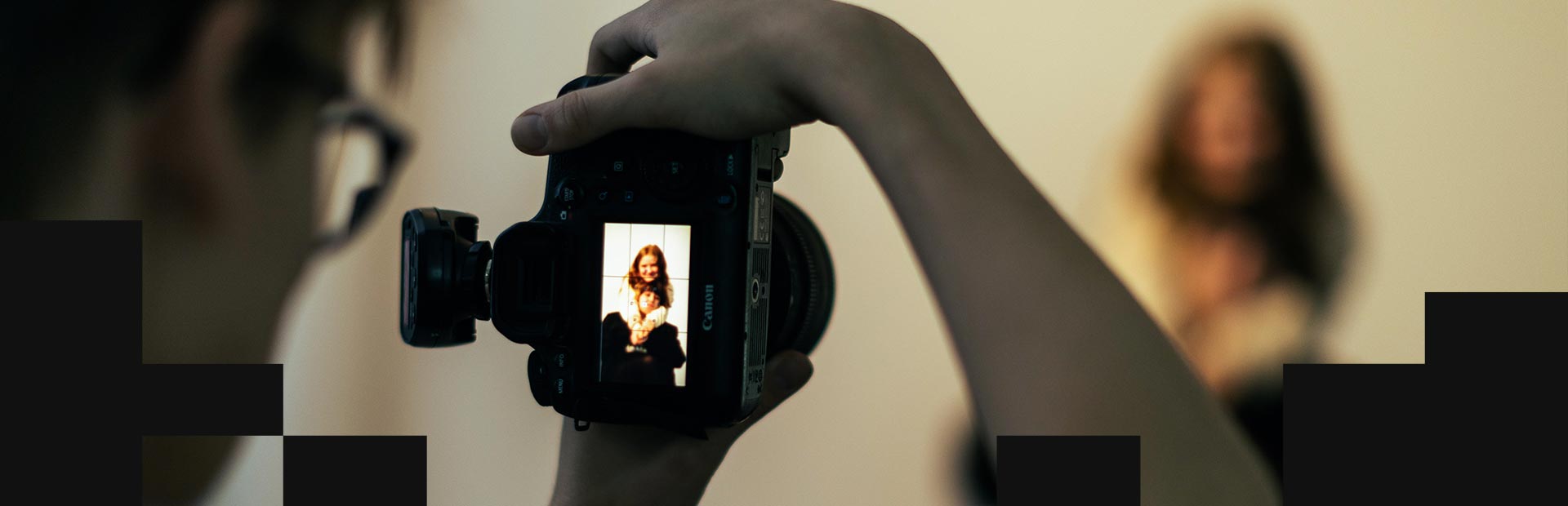 En fotograf tar en bild med en Canon-systemkamera av två tjejer som håller om varandra.