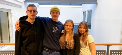 En grupp elever håller om varandra och tittar in i kameran.