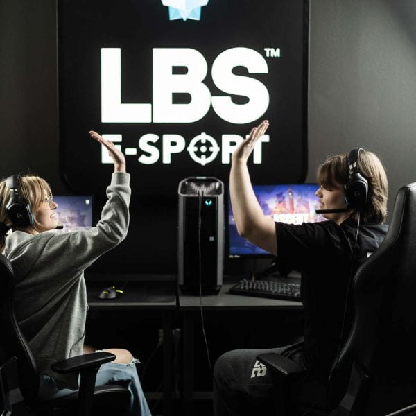 Två elever sitter i e-sport salen och gör high five