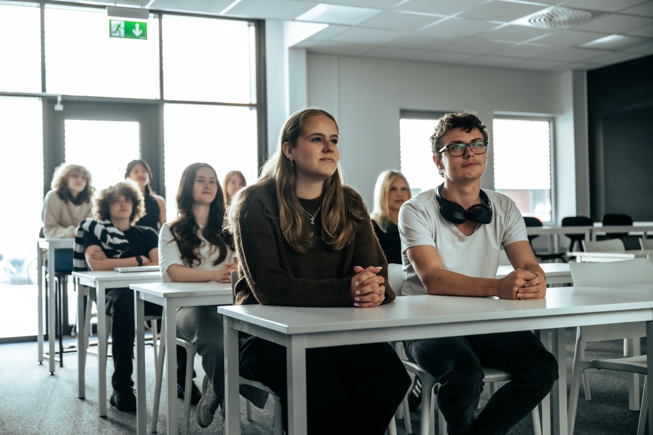 Elever sitter i klassrum och lyssnar på en presentation.