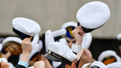 Studenter håller upp sina studentmössor